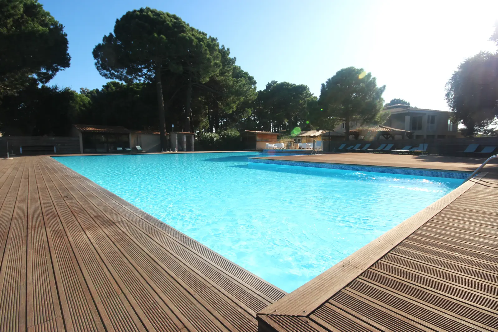 Vue panoramique de la piscine de 350m² avec terrasse en bois